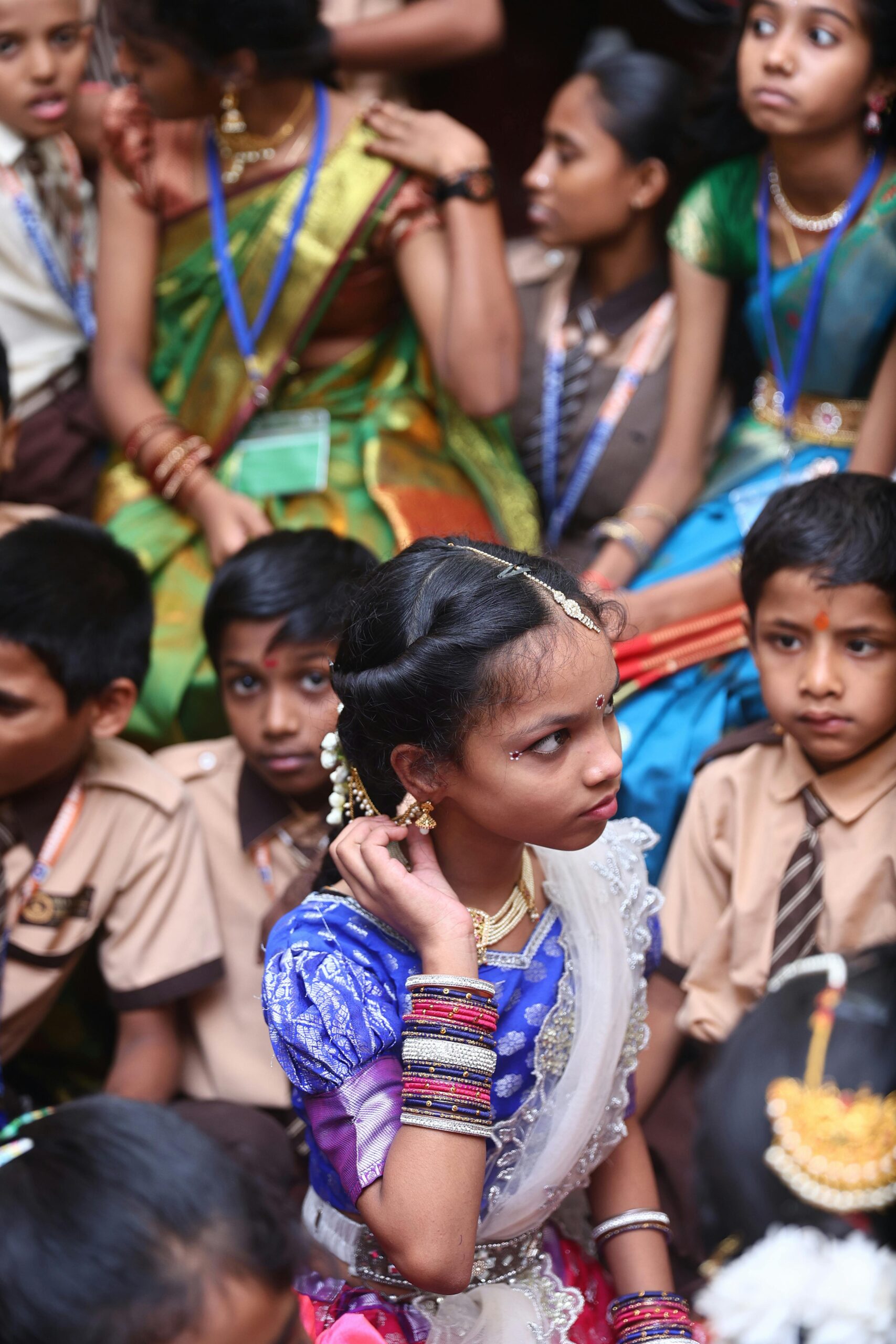 A diverse group of school children dressed in traditional Indian and school uniforms at an event.